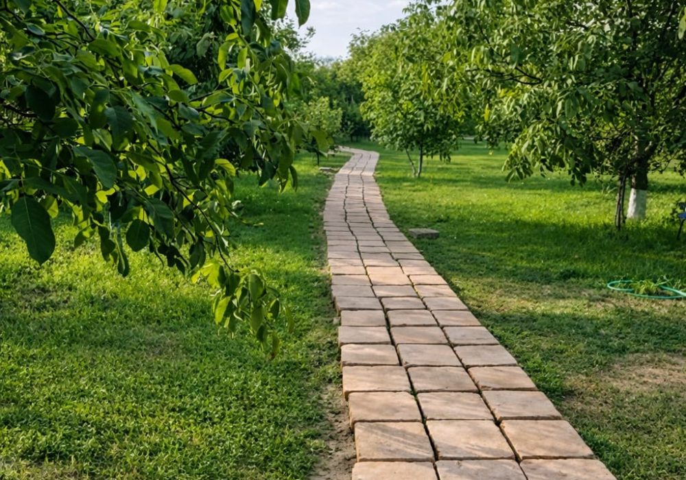 Stone brick path winds through a green park with trees on both sides under a blue sky.